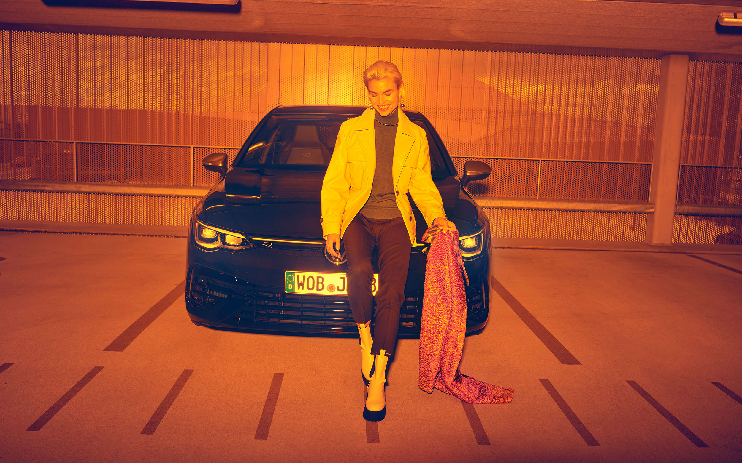 Frau steht vor GOLF-R fotografiert durch orangene Farbfolie